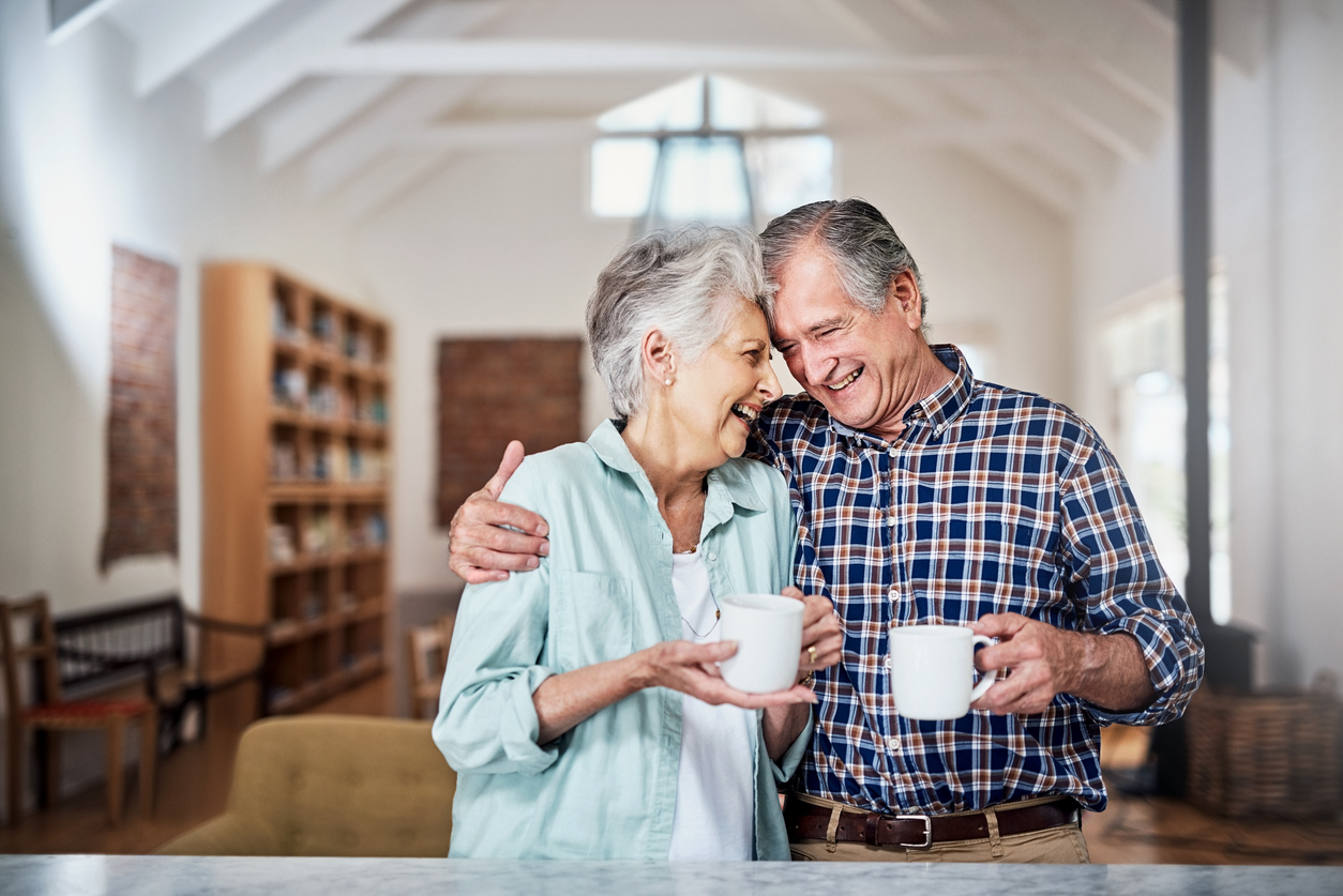 Older couple laughing holding coffee cups