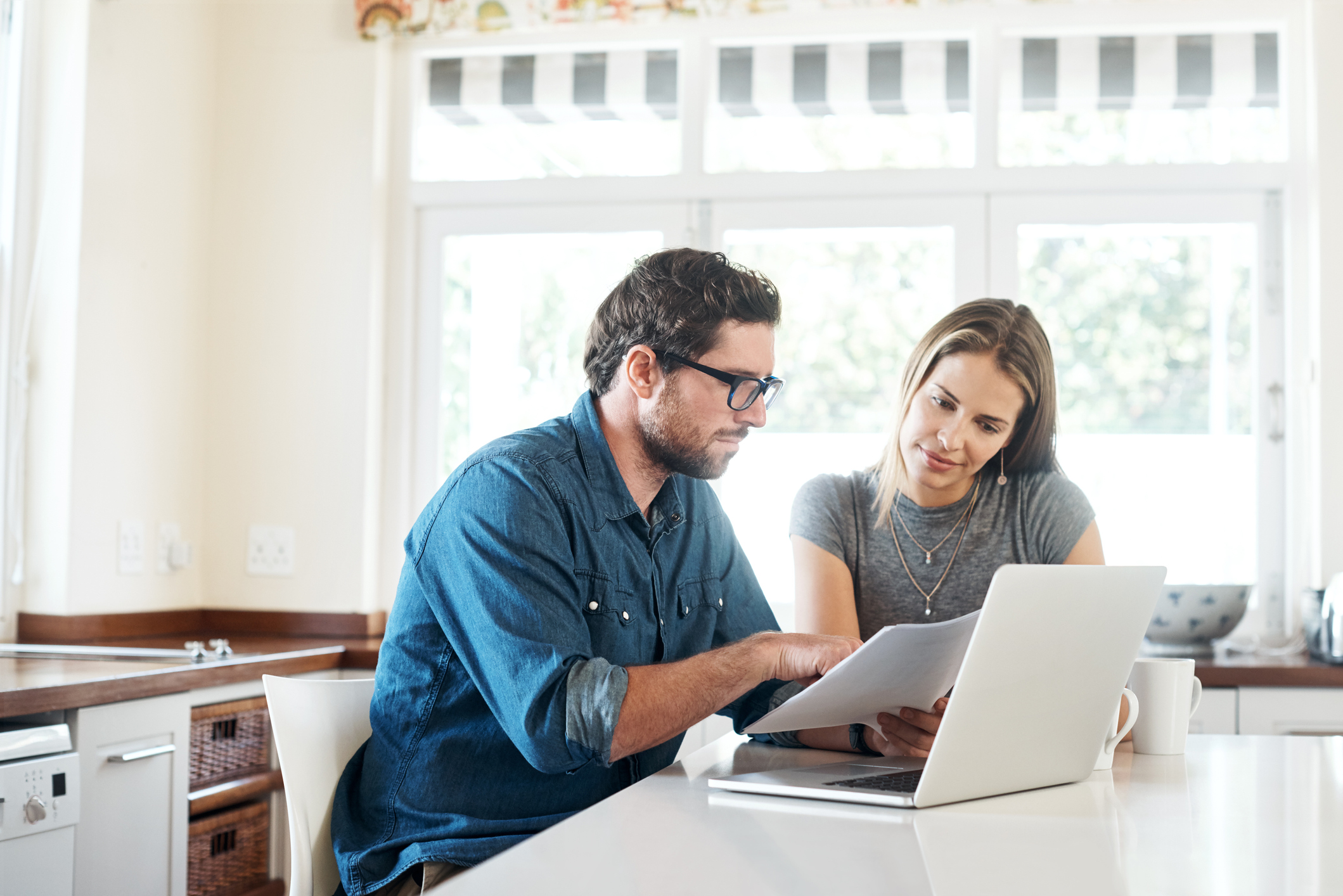 Couple looking at packet of paper over laptop