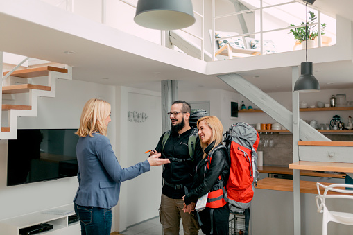 Couple with backpacks on talking to woman in home