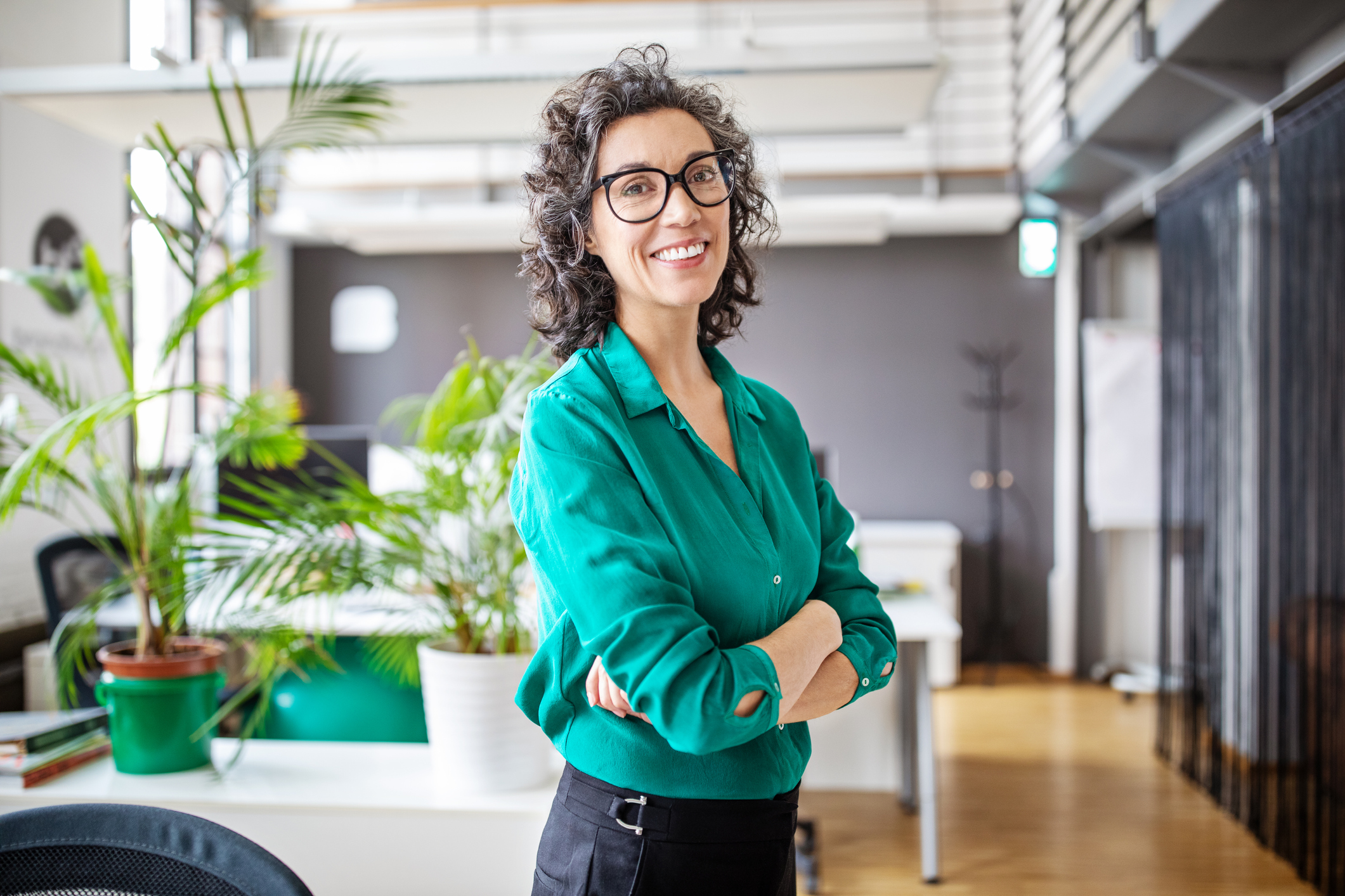 Woman standing in office with arms crossed and smiling